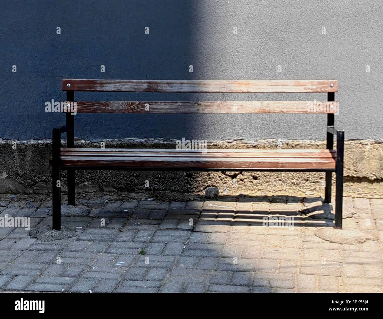 Banc en bois vieilli dans lumière et ombre – scène abstraite urbaine. Banque D'Images