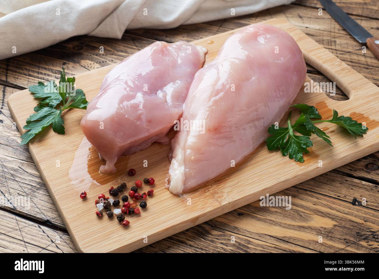 Filet de poitrine de poulet cru sur une planche à découper en bois. Arrière-plan rustique en bois Banque D'Images Filet de poitrine de poulet cru sur une planche à découper en bois. Arrière-plan rustique en bois Banque D'Images