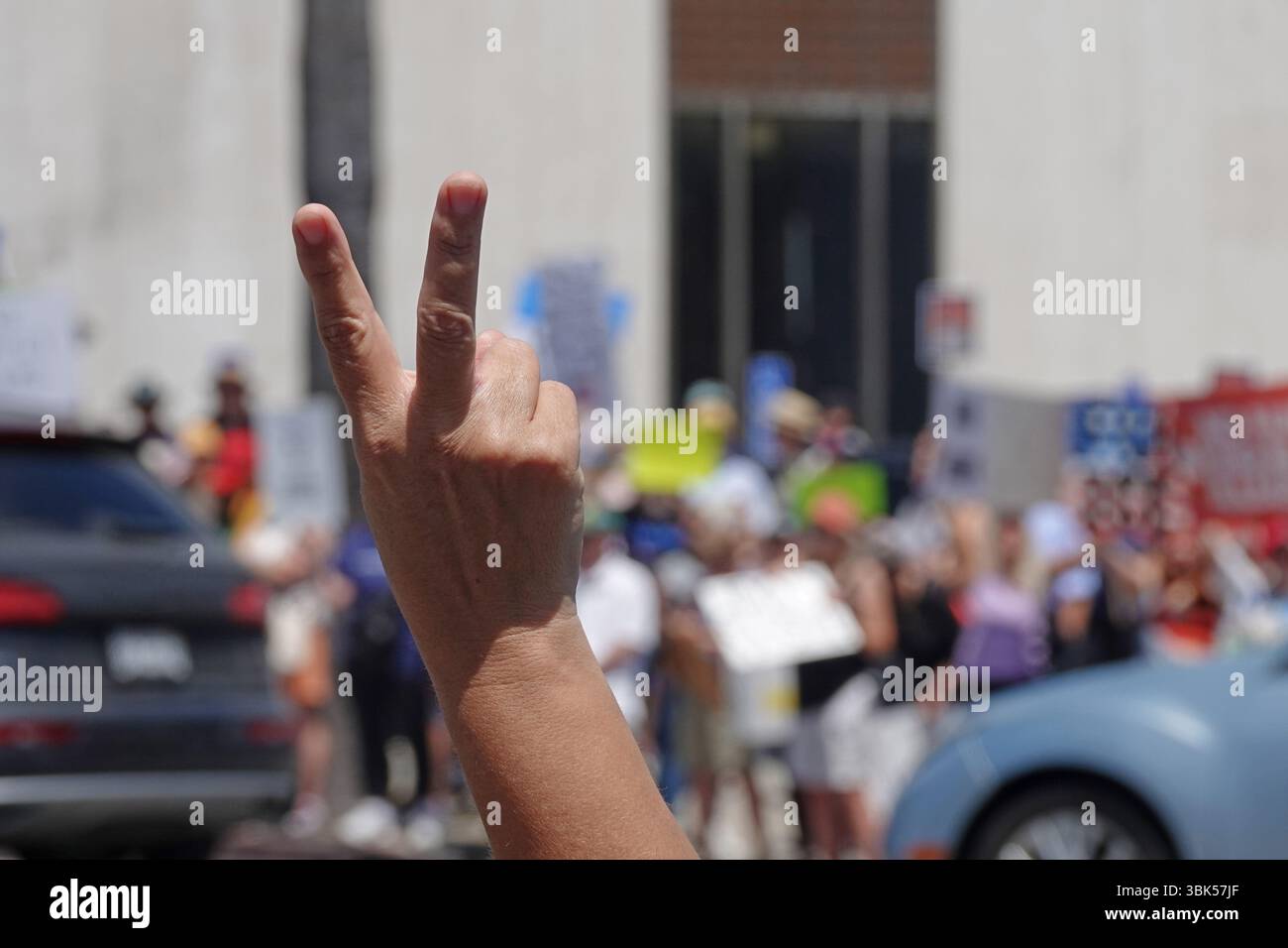 Une main tenant deux doigts comme signe de paix est montrée de près lors d'un rassemblement politique dans une ville. Banque D'Images