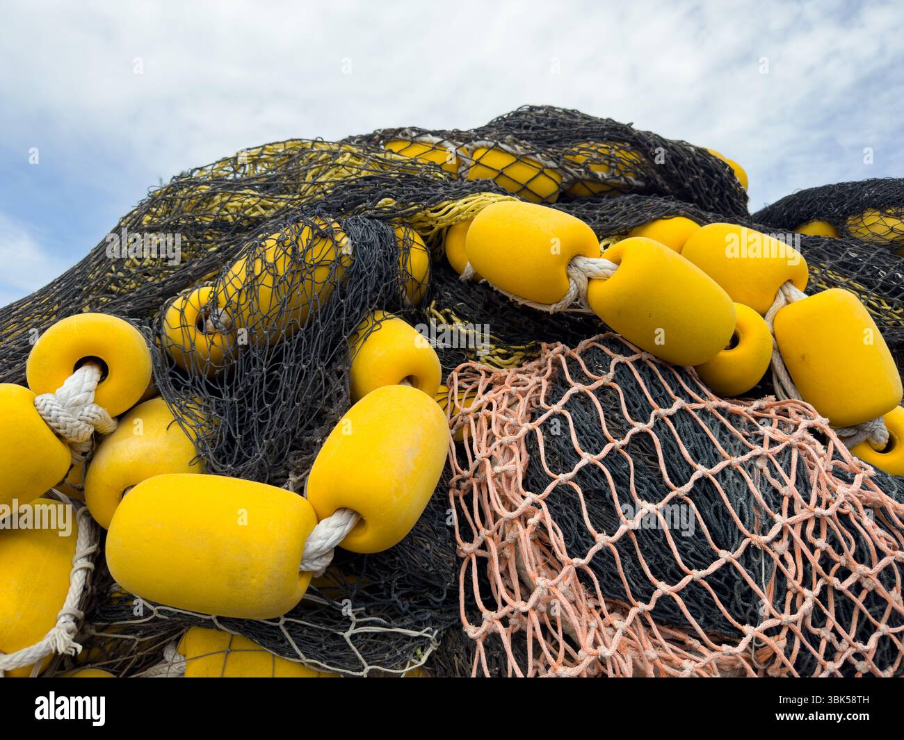 Pile élevée de filets de pêche industriels avec flotteurs jaunes sur corde Banque D'Images