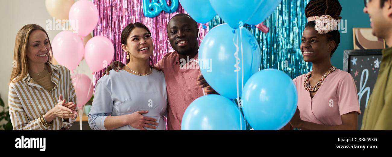 Groupe de jeunes amis multiethniques adultes célébrant la fête de révélation de genre, souriant et interagissant Banque D'Images