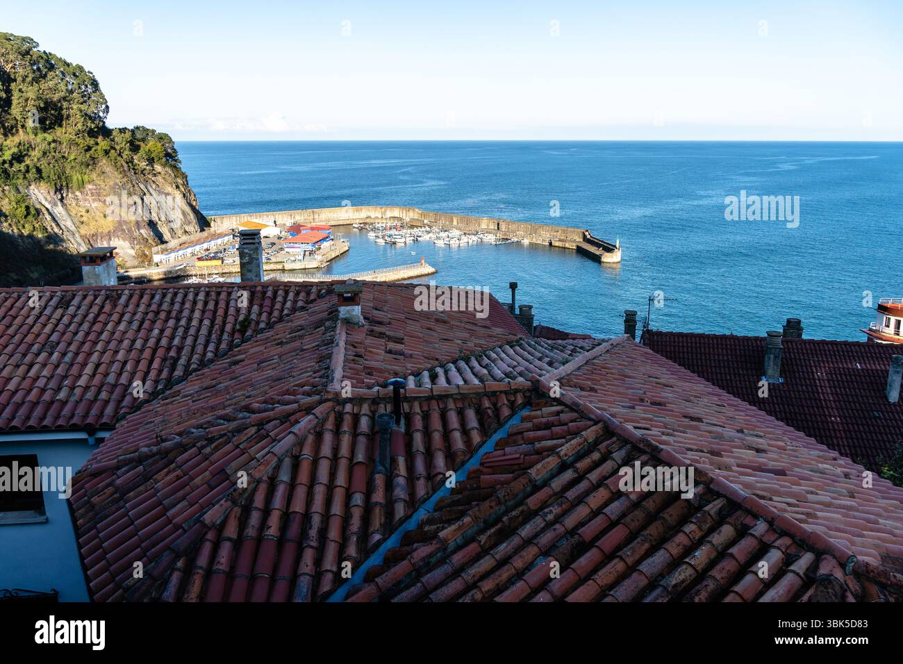 Village côtier vu d'en haut, avec des toits en terre cuite et un port tranquille rempli de bateaux. Lastres, Asturies Banque D'Images