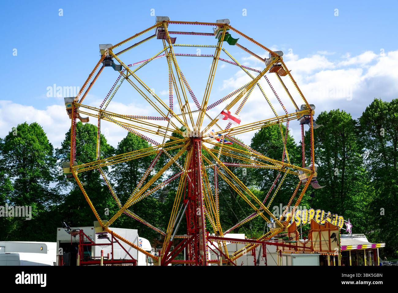 Un tour coloré de foire funfair avec une grande roue sous un ciel bleu à Saffron Walden, Essex, Royaume-Uni. Banque D'Images