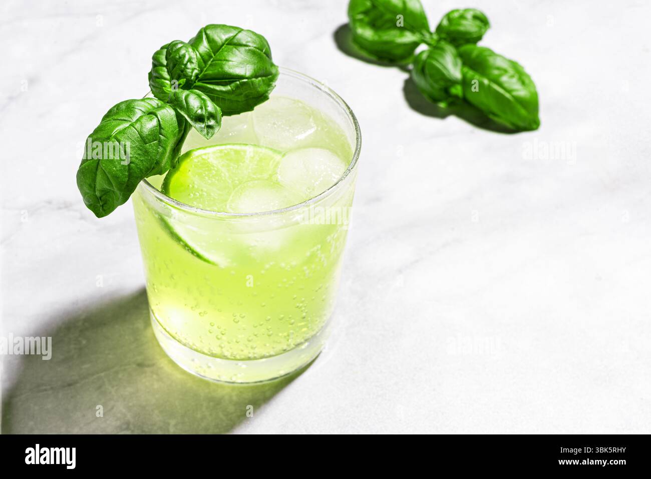 Lime basilic Mocktail avec glace sur fond de marbre blanc, espace de copie. Cocktail vert d'été, tonique rafraîchissant, eau de détox aux agrumes. Basilic smash. Banque D'Images