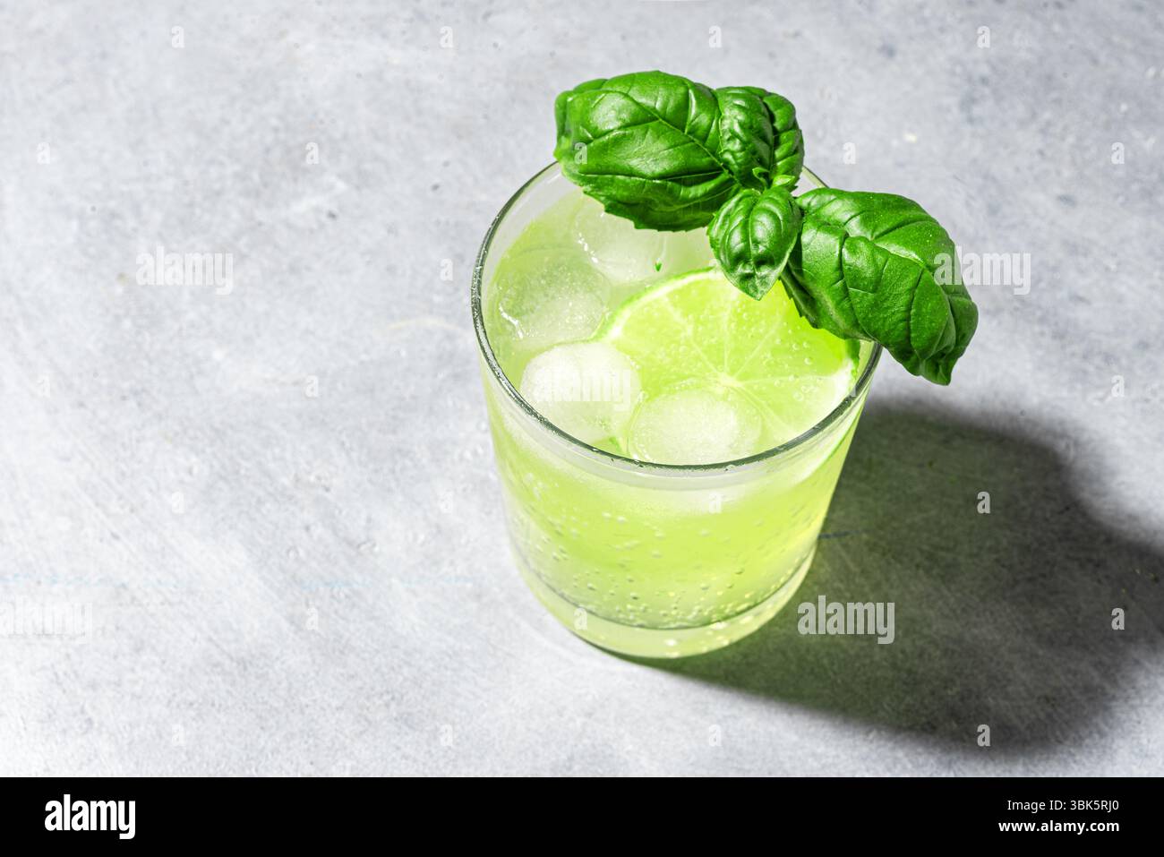 Lime basilic Mocktail avec glace sur fond gris, espace de copie. Cocktail vert d'été, tonique rafraîchissant, eau de détox aux agrumes. Basilic smash. Banque D'Images