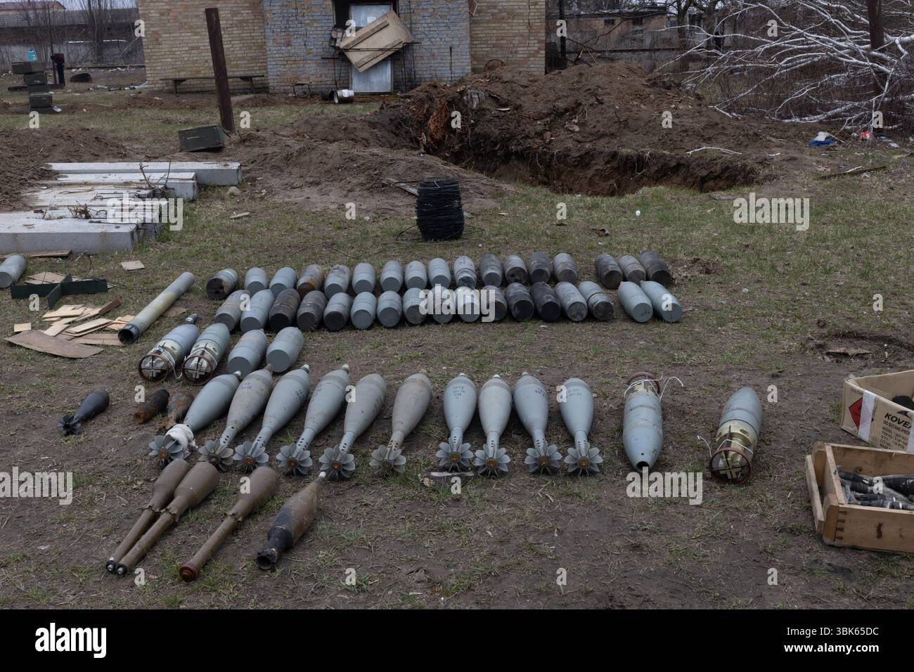 Une variété de munitions militaires ukrainiennes, y compris des obus de mortier et d'autres projectiles, sont posées sur le sol près d'un bâtiment Banque D'Images
