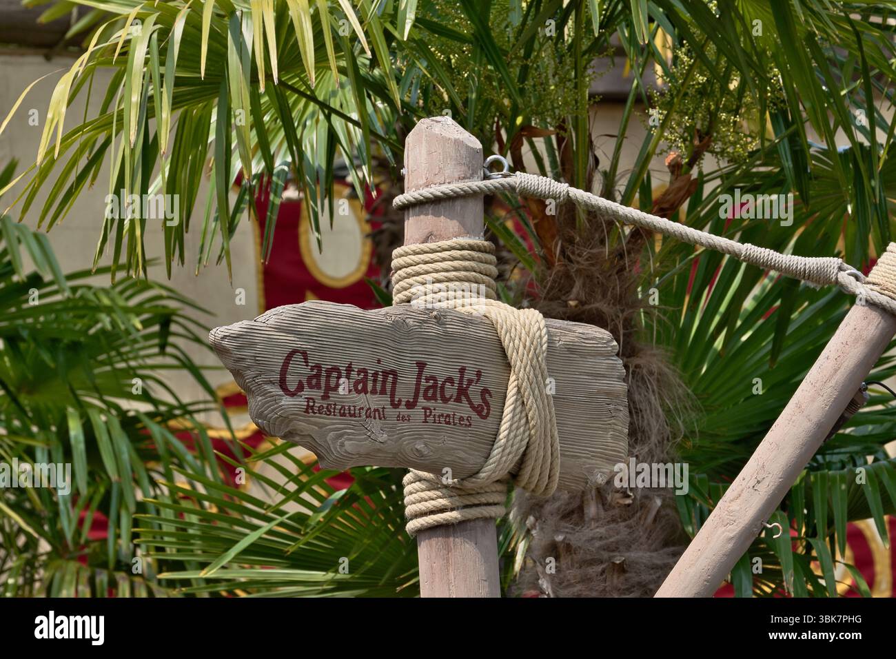 Panneau pour le restaurant Captain Jack's entouré de palmiers, tenu par des poteaux en bois et de la corde à Disneyland Paris, France. Banque D'Images