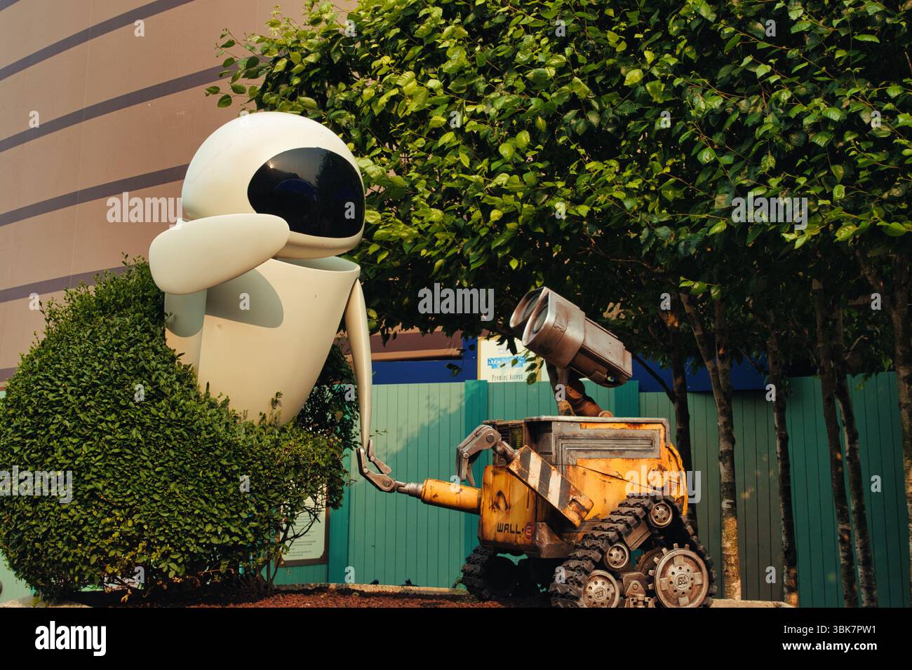 Image montrant des figurines de robot WALL-E et EVE au milieu d'une végétation luxuriante et d'une architecture de fond sous un éclairage chaleureux à Disneyland Paris, France. Banque D'Images