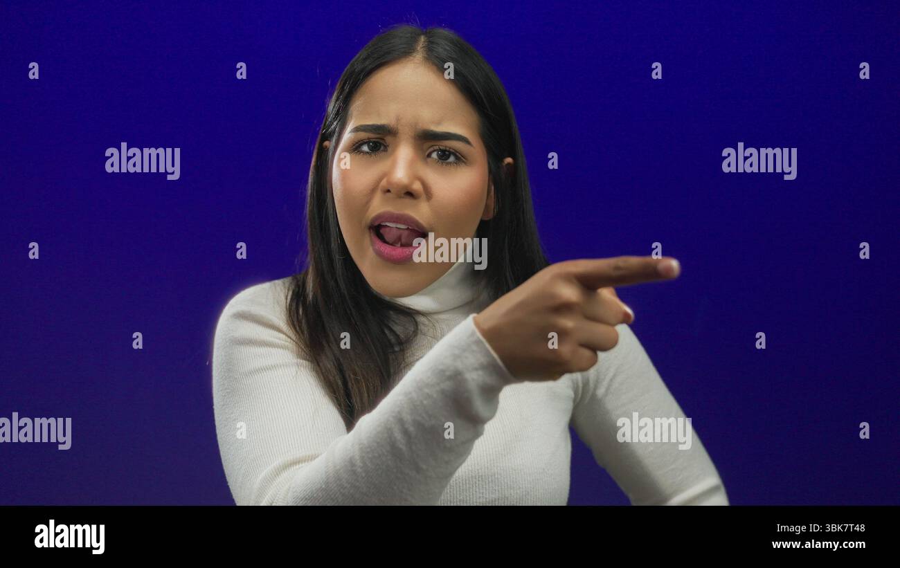 Le doigt d'une femme capturé sur un fond souligne l'identité jeune hispanique latine contre un mur bleu isolé. Banque D'Images