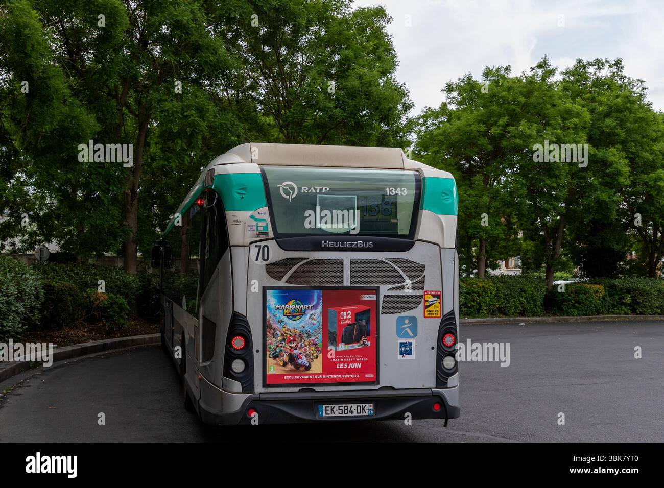 L'arrière d'un bus RATP Heuliez stationné numéro 70 est représenté, orné de publicités pour Nintendo Switch et Mario Kart, avec des arbres verts en arrière-plan. Banque D'Images