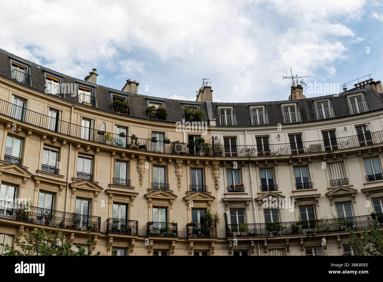 Une photo en bas angle d'une façade de bâtiment courbe avec des balcons, des fenêtres et un ciel nuageux au-dessus. Banque D'Images