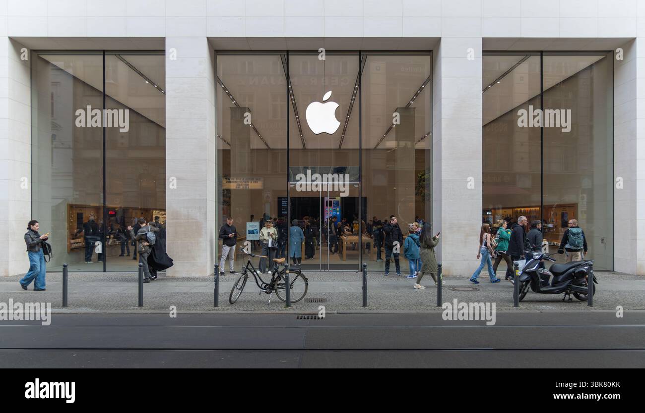 Boutique Apple Store moderne avec façade en verre, piétons passant, personnes entrant et sortant, style de vie urbain dans un quartier commerçant animé. Ber Banque D'Images
