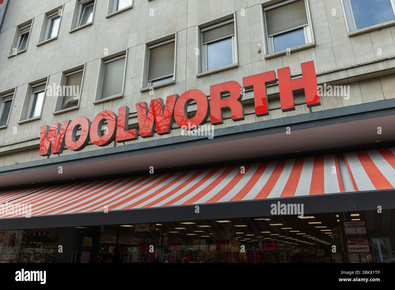 Gros plan de la façade du logo d'un magasin Woolworth avec son panneau rouge et son auvent rayé, suggérant la vente au détail et le shopping. Berlin, Allemagne. 28 mars 2025. Banque D'Images