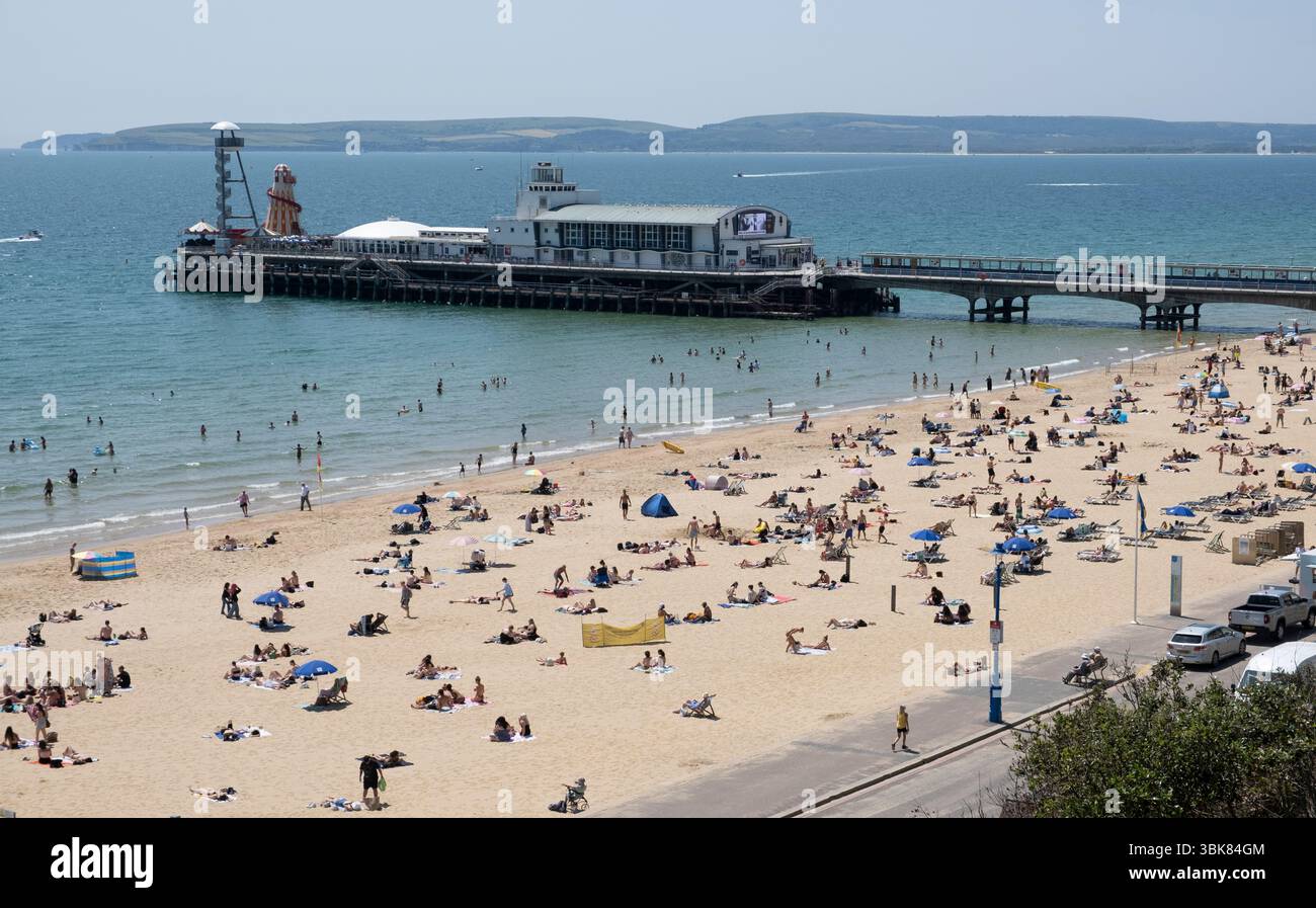 Les amateurs de soleil se rendent à la plage de Bournemouth, Dorset, Angleterre, par une chaude journée de juin. Banque D'Images