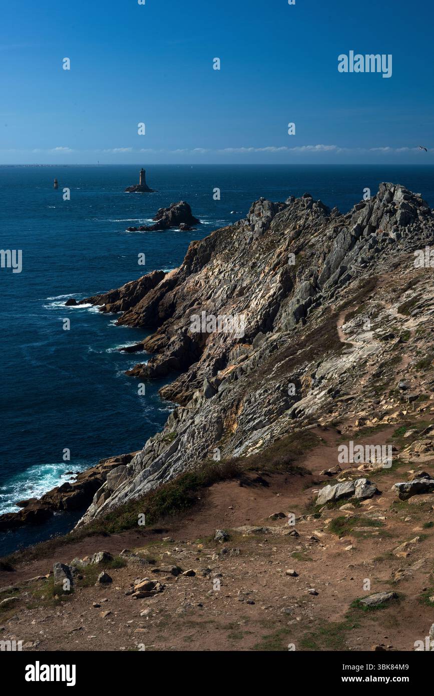 Quatre phares largement répandus guident les navires qui contournent le point accidenté du Raz dans le Finistère, en Bretagne, l’un des points les plus à l’ouest de la France, à travers le canal du Raz de sein entre le continent et la Île de sein, souvent face à des courants atlantiques dangereux, des vagues écrasantes et des vents violents. Banque D'Images