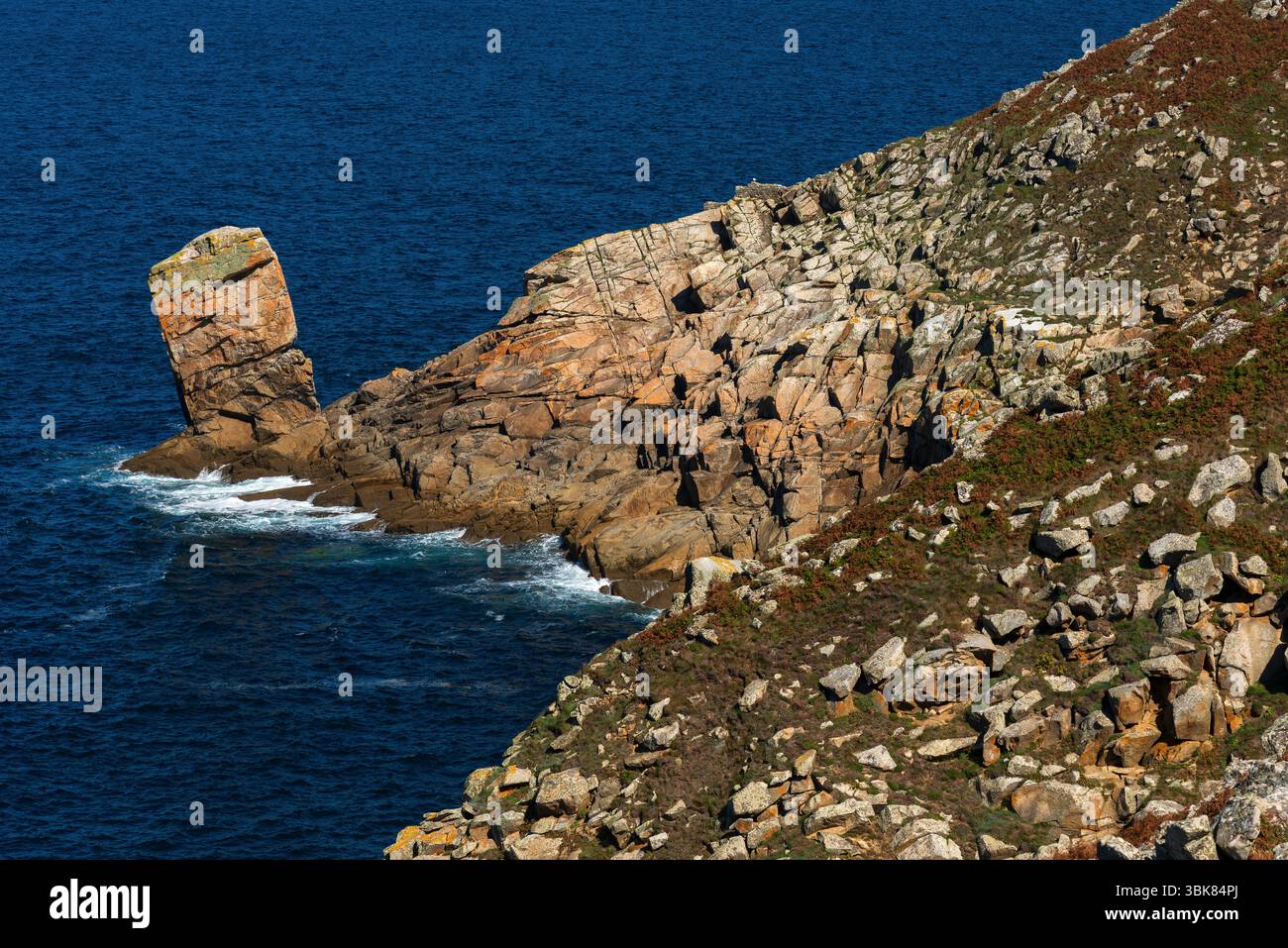 Une aiguille rocheuse inclinée marquée par le temps semble prête à plonger dans l'océan Atlantique depuis la pointe de l'un des promontoires de granit accidentés de la pointe du Raz dans le Finistère, en Bretagne, en France, l'un des points les plus à l'ouest du continent français. La péninsule spectaculaire est l'un des grands sites de France, renommé pour leur beauté naturelle préservée. Banque D'Images