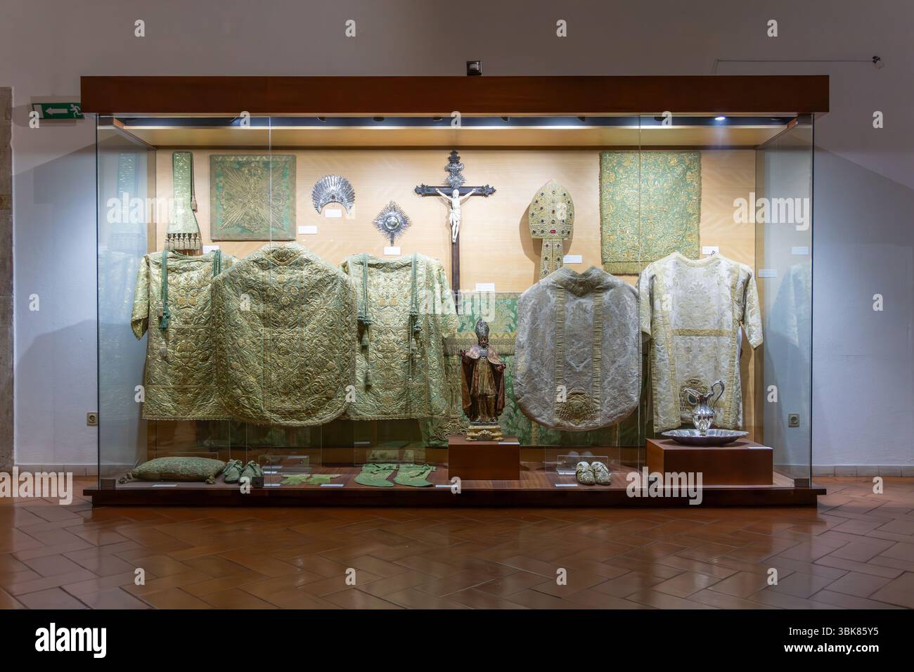 Une vitrine en verre dans l'église du monastère de São Vicente de Fora exposant des vêtements religieux ornés, y compris des chasubles, des mitres et des objets liturgiques Banque D'Images