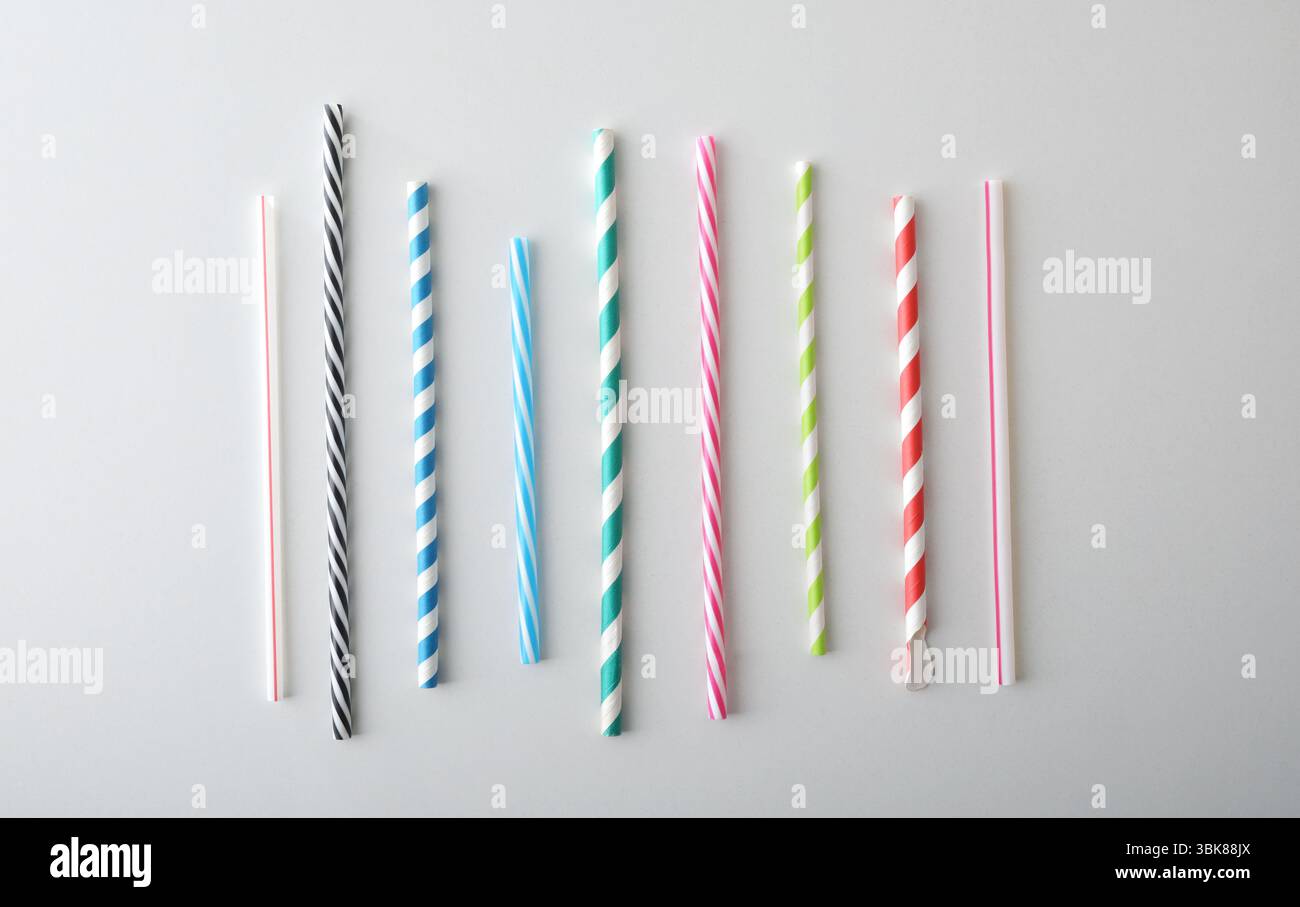Collection de pailles tubulaires à boire avec différents motifs et couleurs isolés sur une table blanche. Vue de dessus. Banque D'Images