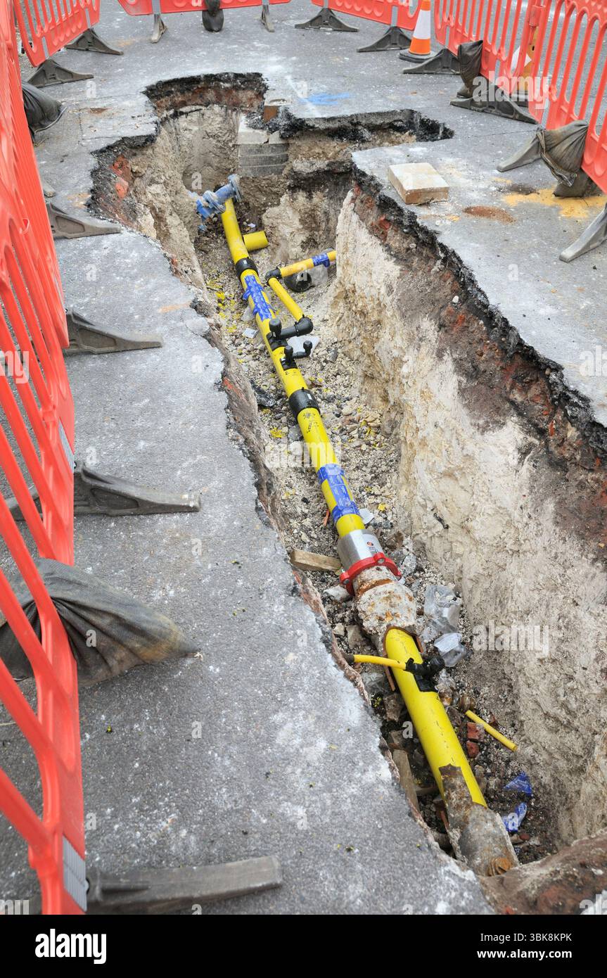 Travaux de remplacement de la conduite principale de gaz en cours montrant un trou de tranchée creusé avec un tuyau de gaz souterrain sous la surface de la route. Conduites de gaz. Greater London, Angleterre Royaume-Uni Banque D'Images