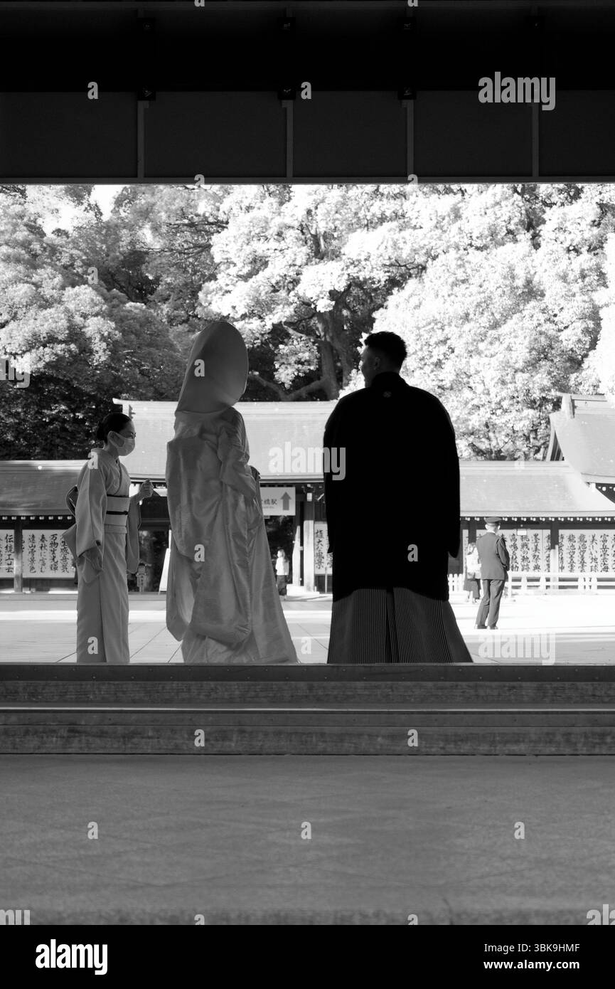 Mariée et mariée en tenue traditionnelle se tiennent dans un reflet tranquille au sanctuaire Meiji Jingu Banque D'Images