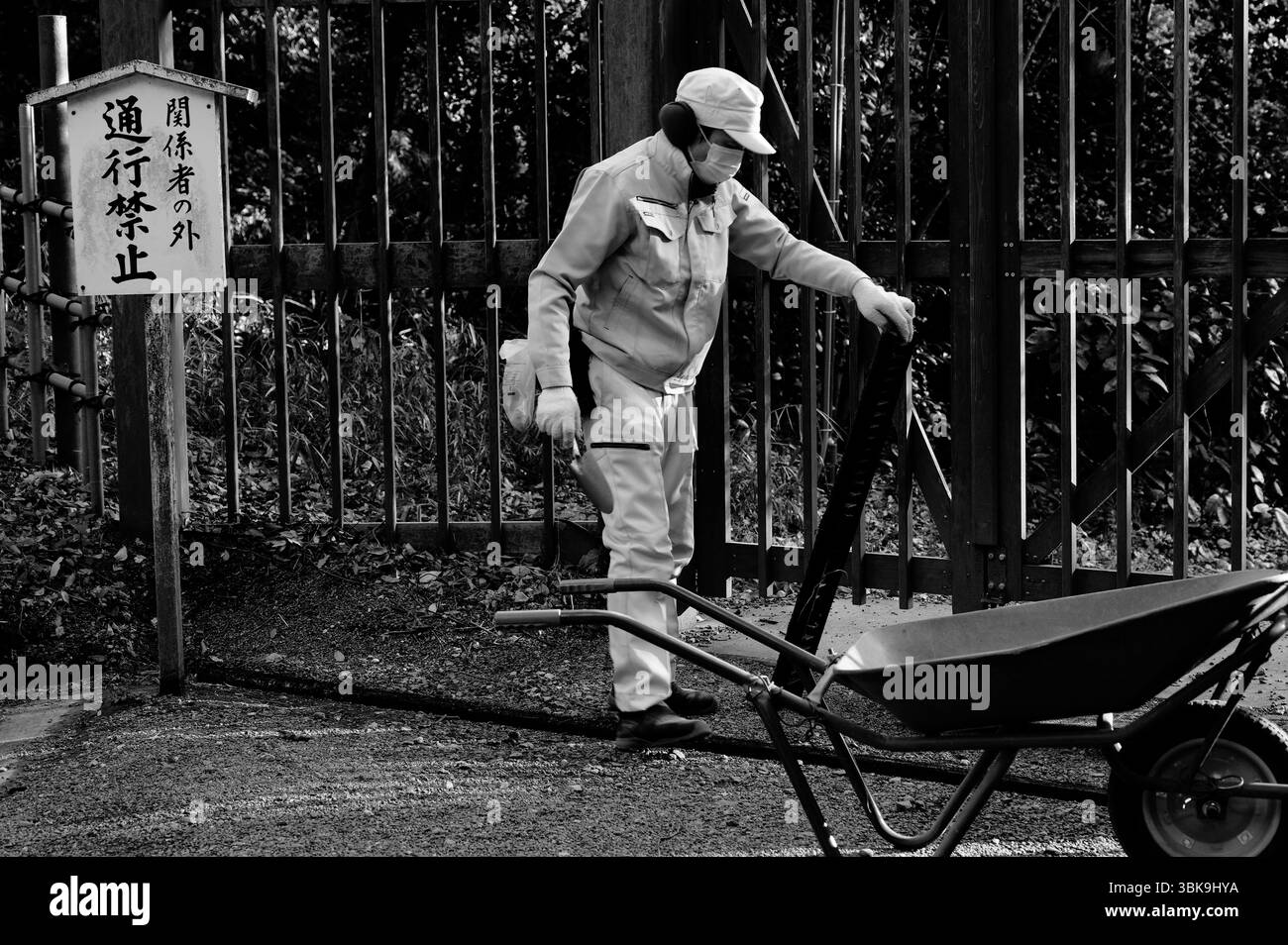 Un travailleur du parc nettoie les débris de gouttière près d'une barrière restreinte dans le parc Yoyogi Banque D'Images