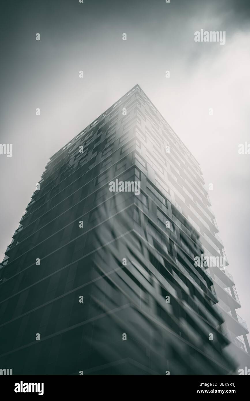 Bâtiment en verre avec prise de vue en angle de ciel nuageux foncé Banque D'Images