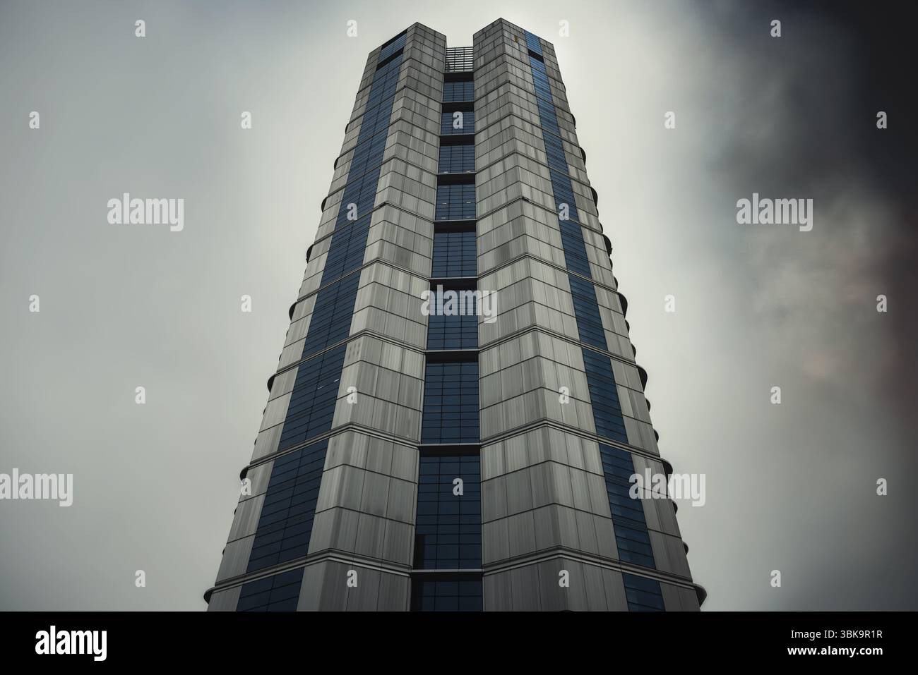 Bâtiment en verre avec prise de vue en angle de ciel nuageux foncé Banque D'Images