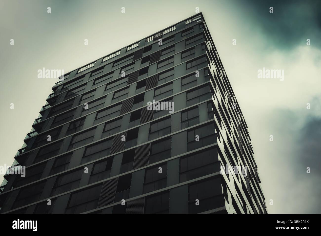 Bâtiment en verre avec prise de vue en angle de ciel nuageux foncé Banque D'Images