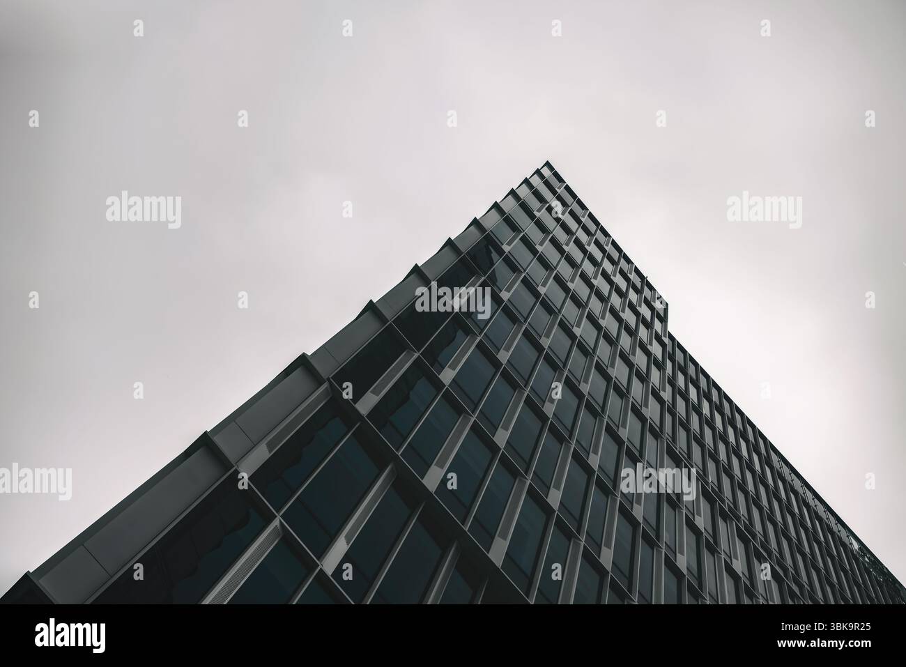 Bâtiment en verre avec prise de vue en angle de ciel nuageux foncé Banque D'Images