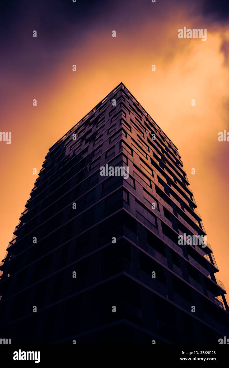 Bâtiment en verre avec prise de vue en angle de ciel nuageux foncé Banque D'Images