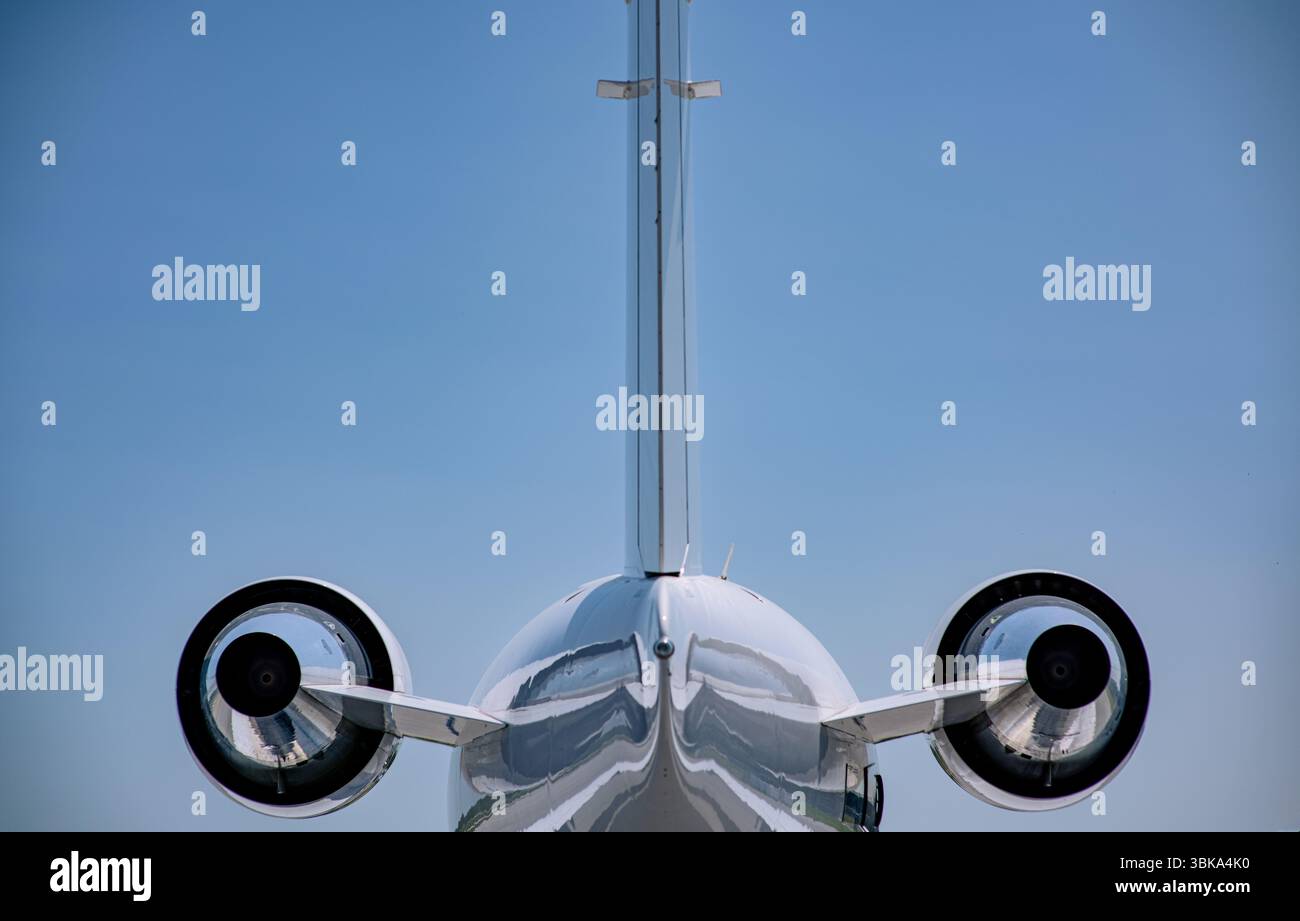 Vue arrière d'un avion d'affaires bimoteur montrant des nacelles polies et un stabilisateur vertical sous un ciel bleu clair. Banque D'Images