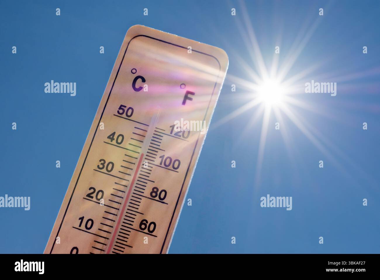 Thermomètre affichant une température élevée avec un soleil radieux sur un fond de ciel bleu. Concepts d'été, temps chaud, canicule, etc Banque D'Images