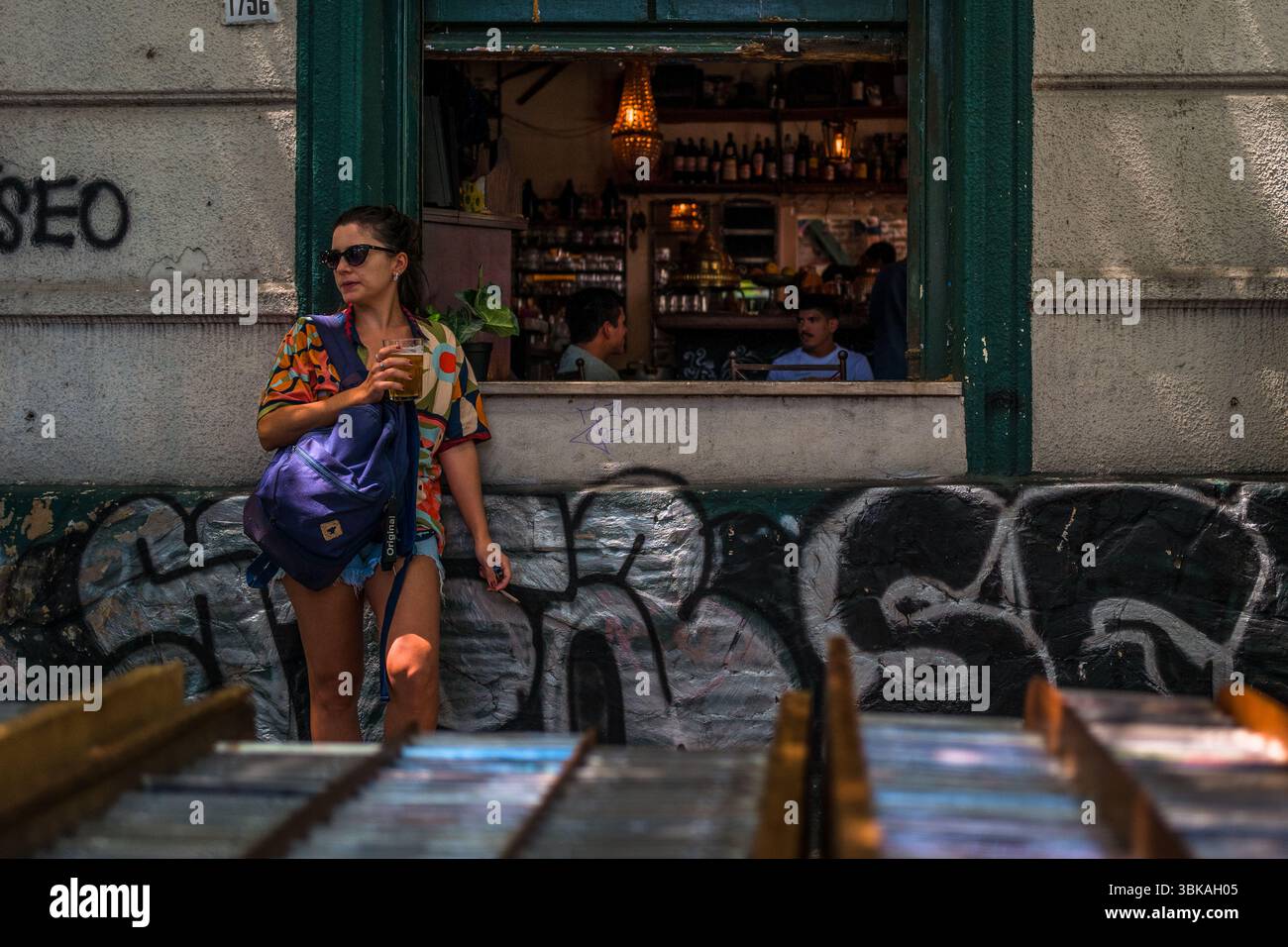Une uruguayenne boit de la bière devant un restaurant de style ancien au marché de rue Tristán Narvaja à Montevideo, en Uruguay. Banque D'Images