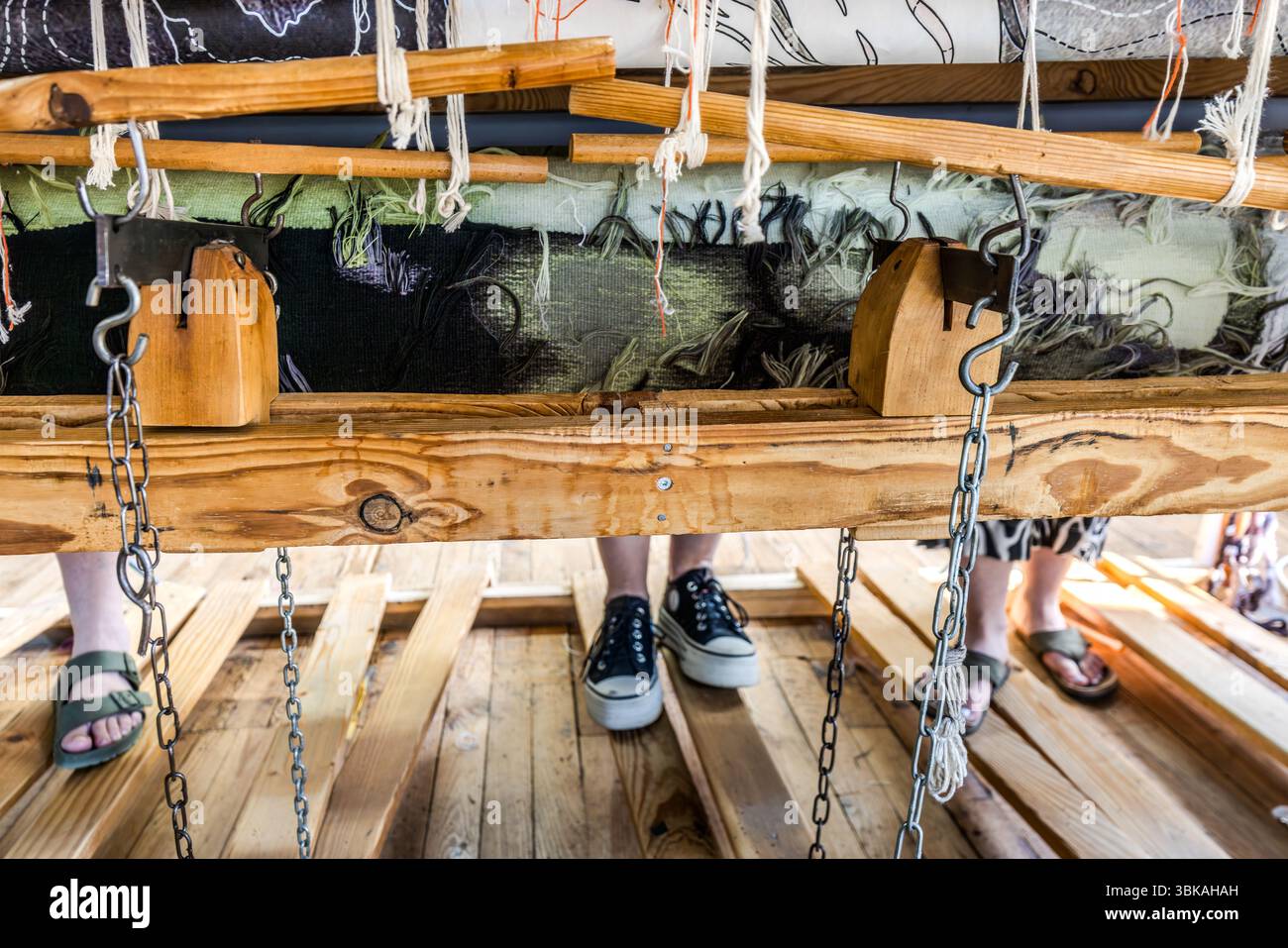 Une vue sous le métier à tisser plat (basselisse) sur lequel trois tisserands de l'atelier Robert four d'Aubusson produisent la tapisserie de Françoise Petrovitch 'hommage à George Sand' à l'occasion du 150e anniversaire de la mort de George Sand. Les sections terminées de la tapisserie de 23 mètres de long sont enroulées à nouveau et ne peuvent être vues que de l'arrière. Même les tisserands ne seront pas en mesure de voir le travail complet jusqu'au jour où il est retiré du métier à tisser. Rue Madeleine, Aubusson, Nouvelle-Aquitaine, France Banque D'Images