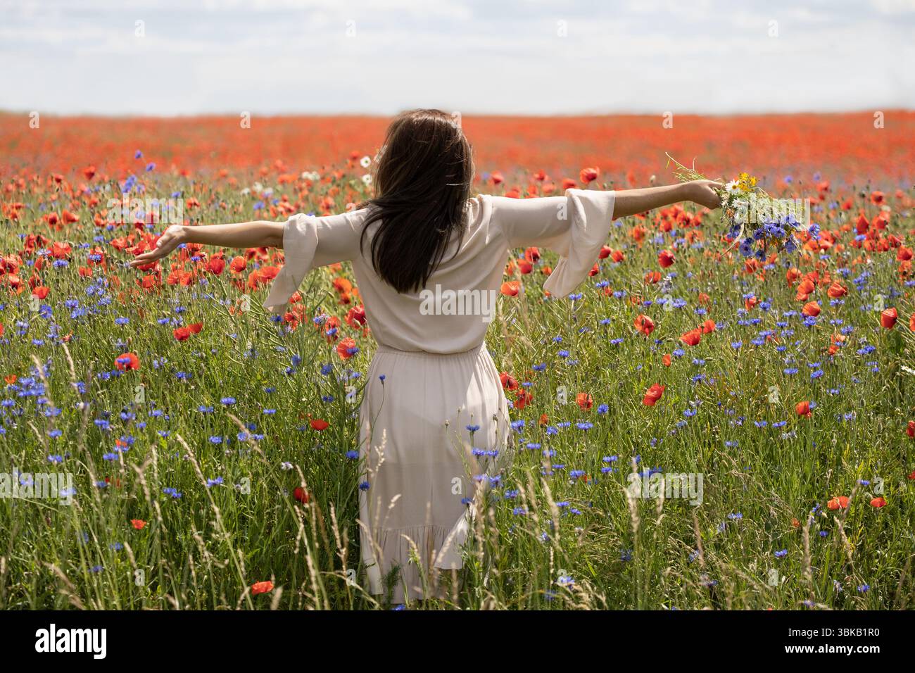 Femme dans le champ de fleurs avec les bras tendus Banque D'Images