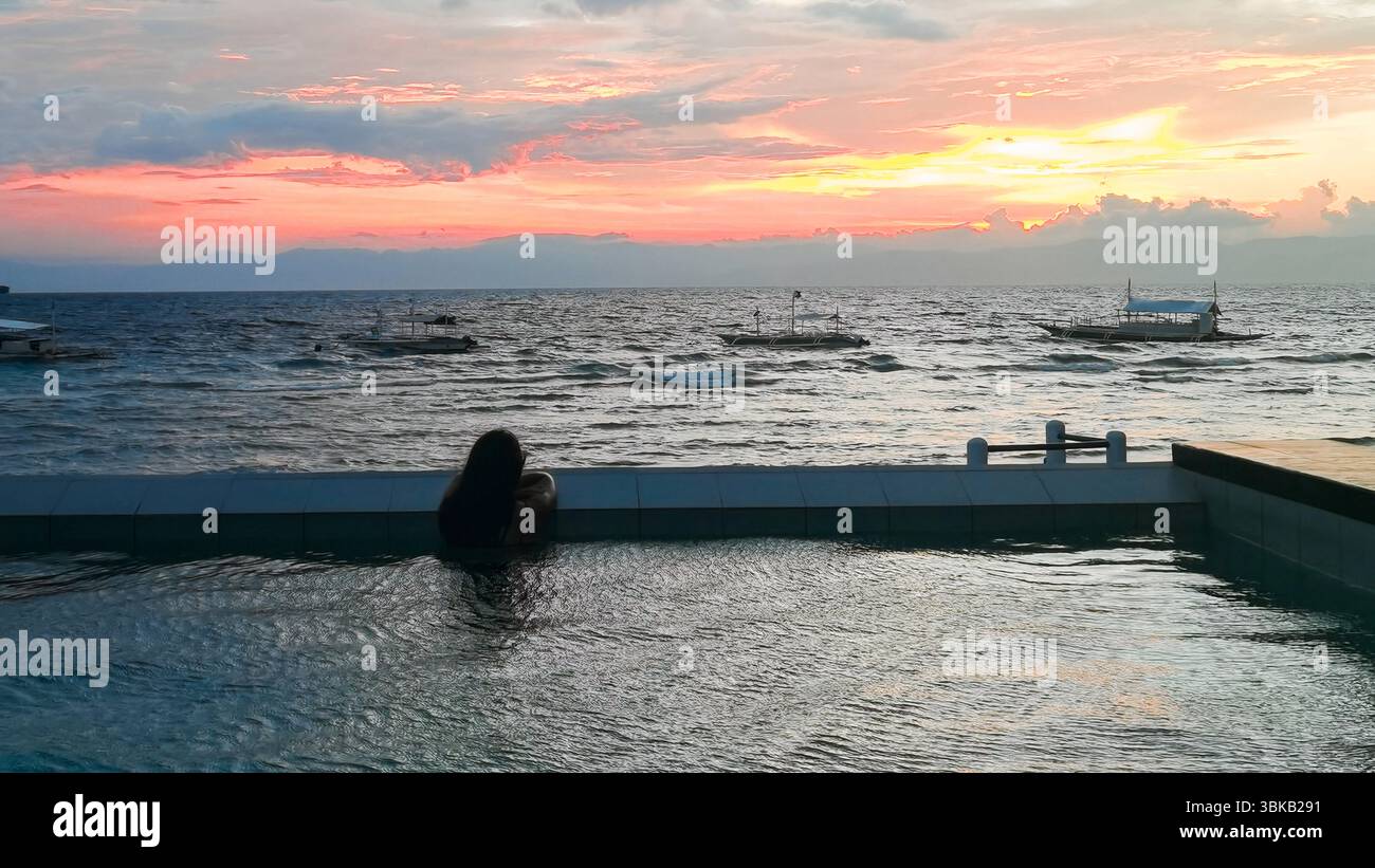 Piscine à débordement, eau turquoise, vue sur l'océan - Une piscine turquoise spectaculaire se mélange avec la mer bleue au-delà, évoquant le luxe pur, la joie et la relaxation profonde Banque D'Images