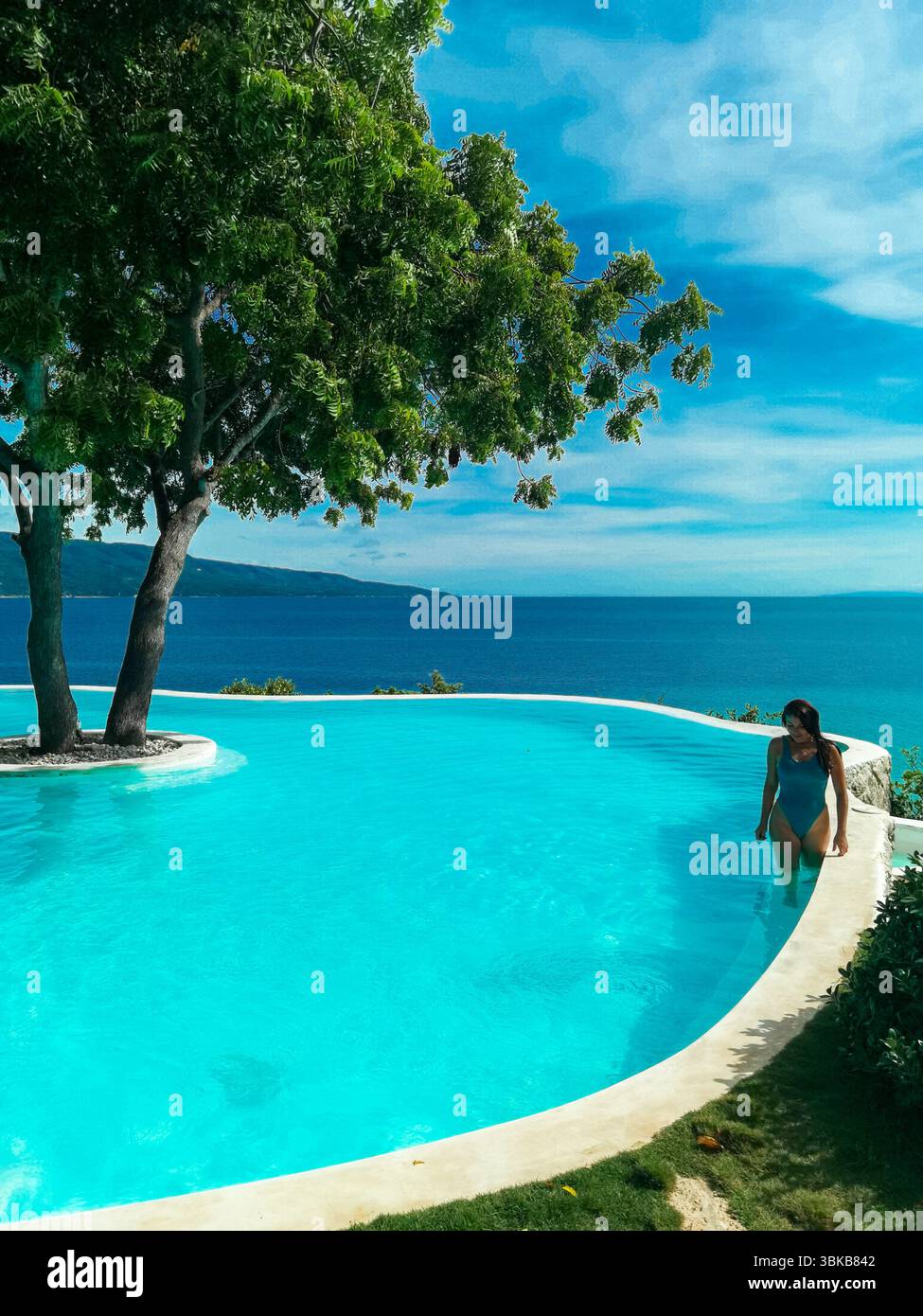 Piscine à débordement, eau turquoise, vue sur l'océan - Une piscine turquoise spectaculaire se mélange avec la mer bleue au-delà, évoquant le luxe pur, la joie et la relaxation profonde Banque D'Images