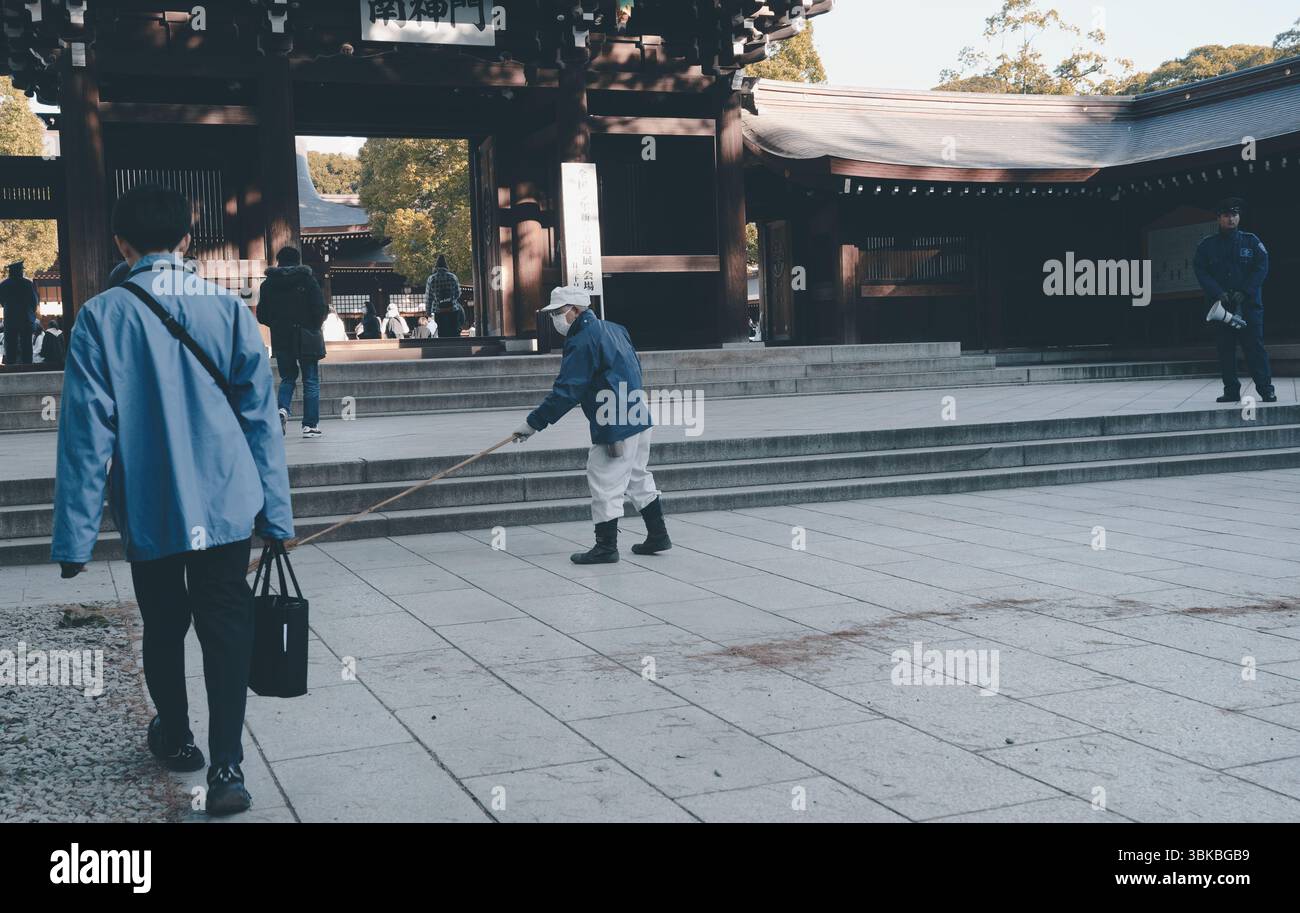 Un travailleur balaie soigneusement l'approche du sanctuaire Meiji Jingu Banque D'Images