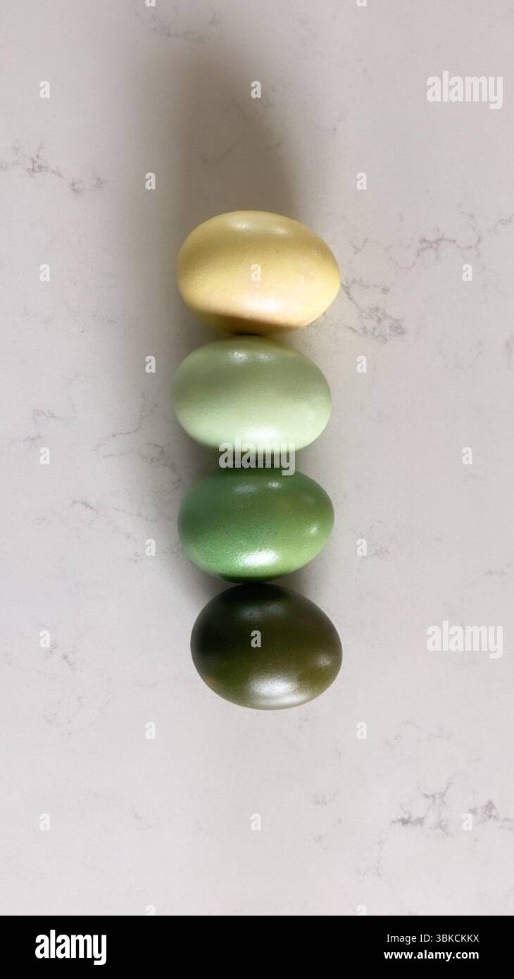 Quatre oeufs de couleur dégradé en jaune et vert empilés verticalement Banque D'Images