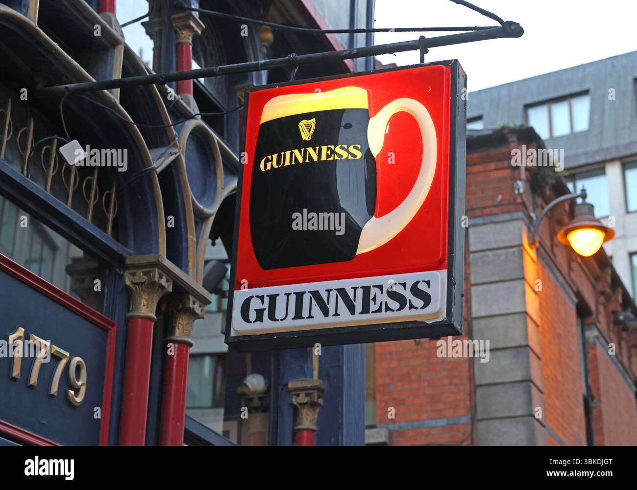 Signe traditionnel Guinness au crépuscule devant un bar à Dublin, Irlande Banque D'Images