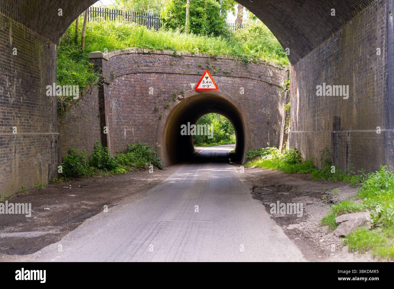 Pont bas en béton sur un tunnel étroit le long d'une route de campagne traversant la campagne anglaise Banque D'Images