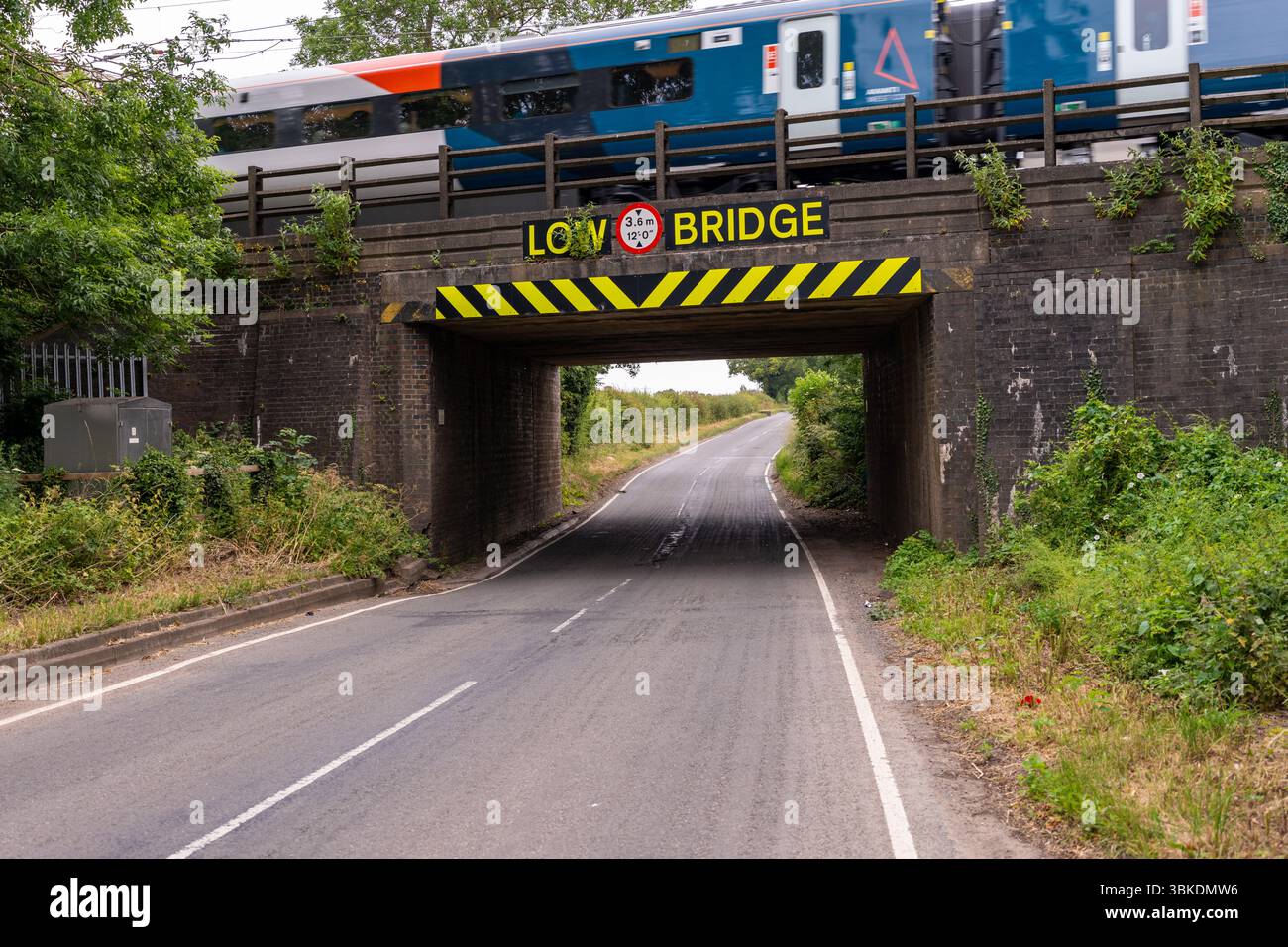 Train rapide roulant sur un pont bas sur une route de campagne au Royaume-Uni, mettant en valeur des paysages ruraux et des merveilles d'ingénierie Banque D'Images