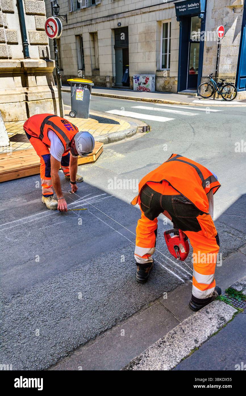 Ouvriers routiers utilisant un outil 'craie' pour marquer la surface de la route pour les lignes peintes - Tours, Indre-et-Loire (37), France. Banque D'Images