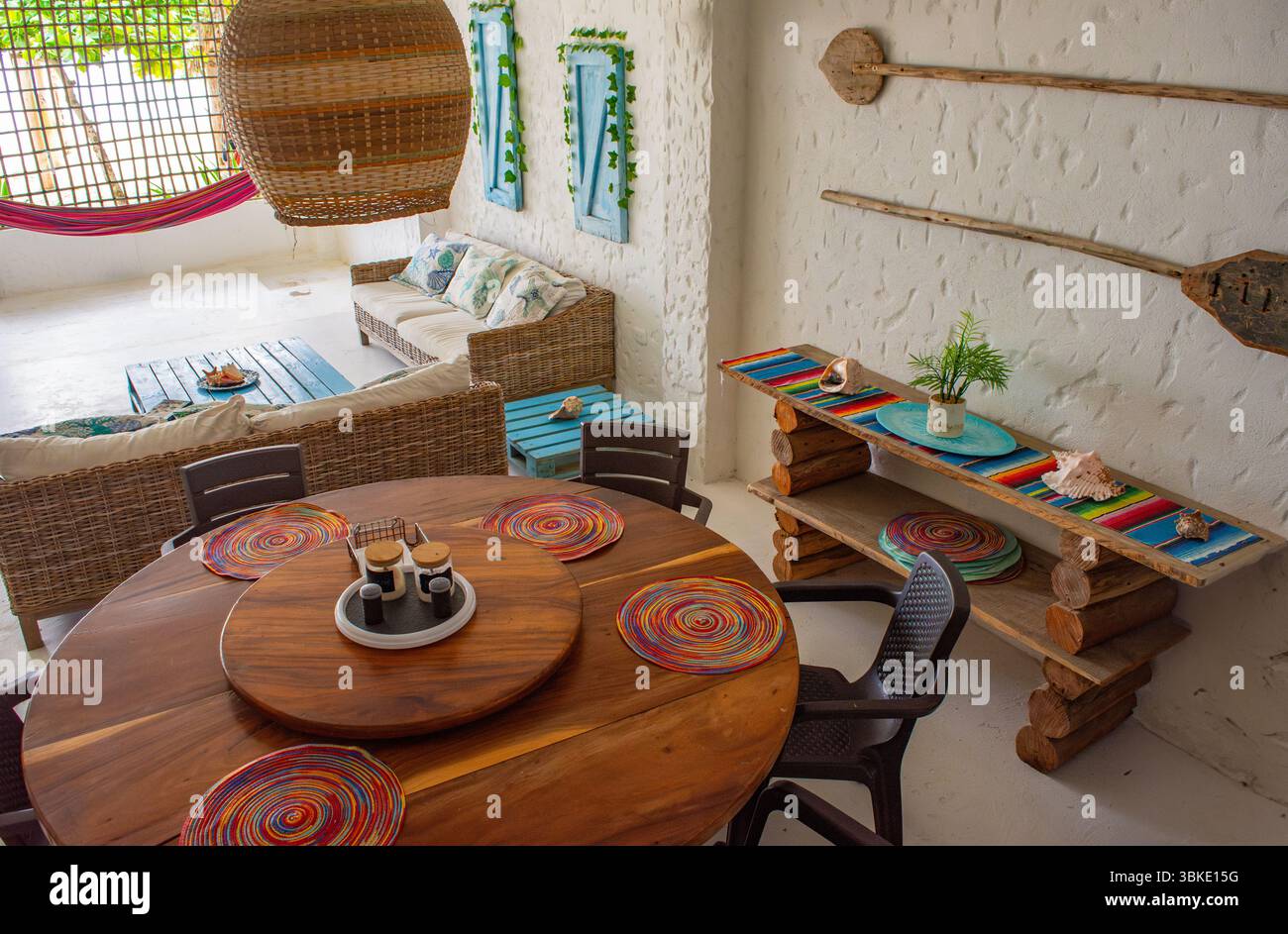 Charmant intérieur d'une maison de vacances côtière avec une table à manger en bois, un décor vibrant et un coin salon confortable à Rincon del Mar. Banque D'Images