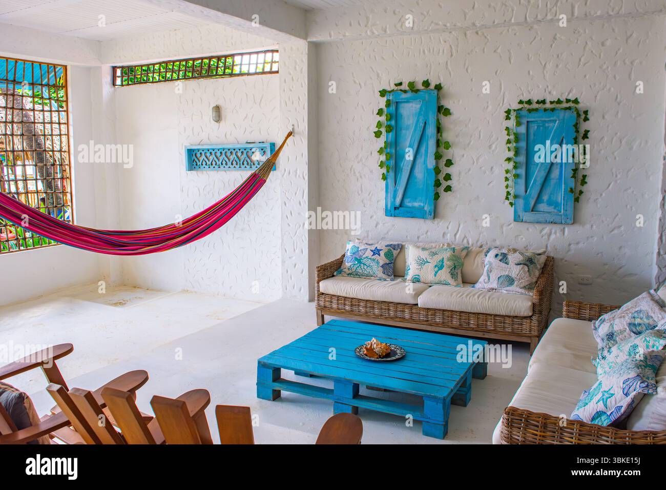 Espace de vie côtier lumineux et accueillant avec un hamac coloré, des meubles en osier et un décor élégant, parfait pour la détente à Rincon del Mar. Banque D'Images