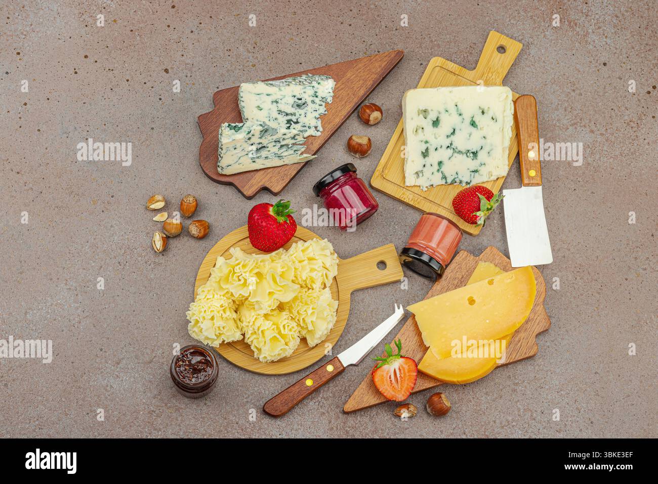 Assortiment de fromages sur fond rustique avec des noix, des fraises et de la confiture. Comprend Tête de moine, Roquefort, Saint Agur et Gouda sur planches de bois, top Banque D'Images