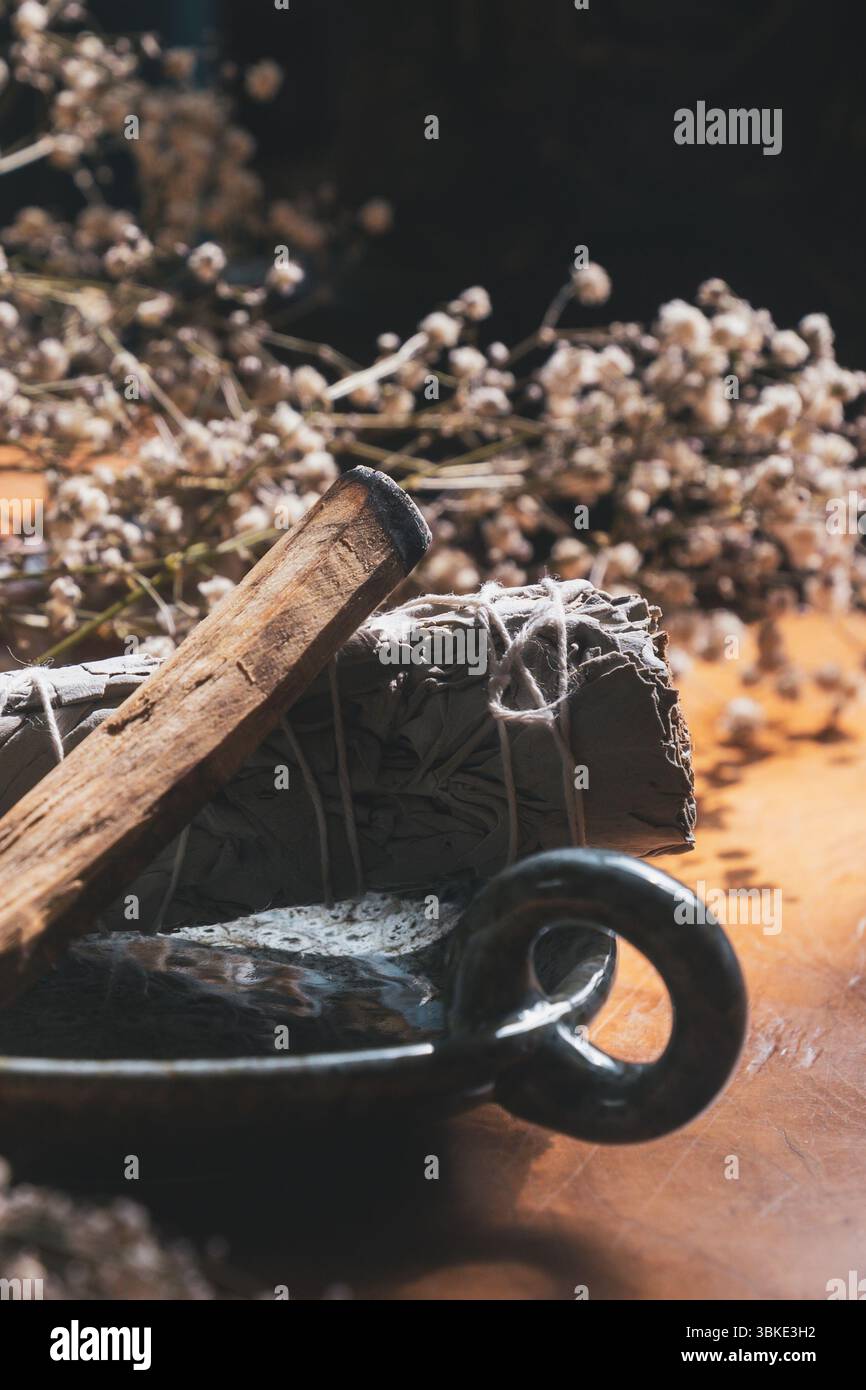 Palo Santo et la sauge bavent sur un plat en céramique entouré de fleurs séchées Banque D'Images