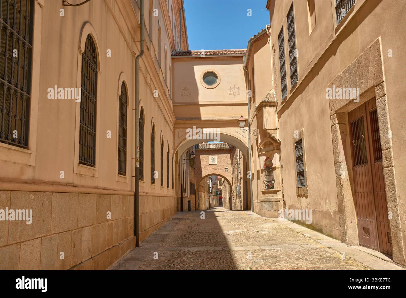 La rue Encarnacion dans la vieille ville de Plasencia est un étroit passage pavé flanqué de grands bâtiments dans des tons ocre et sable, Banque D'Images