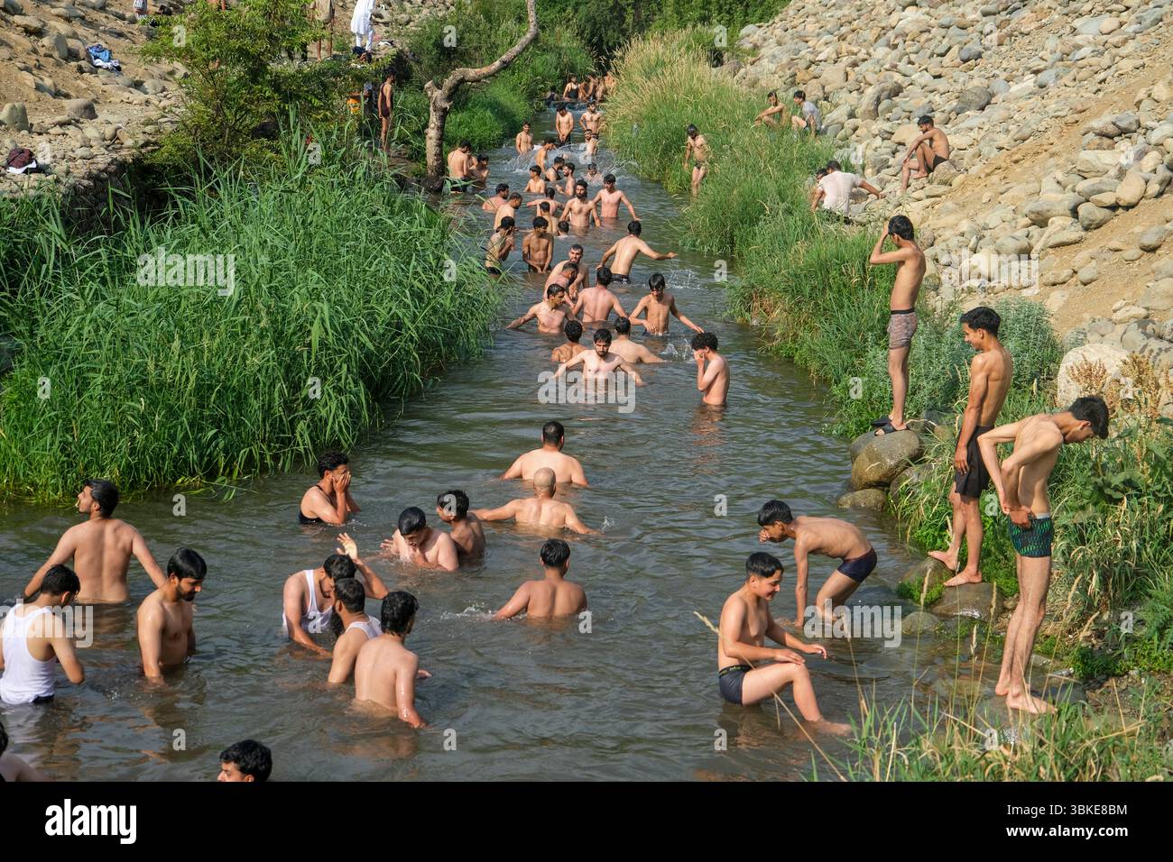Srinagar, Inde. 20 juin 2025. Les gens se rafraîchissent dans un ruisseau pendant une chaude journée d'été dans la banlieue de Srinagar. De fortes vagues de chaleur balayent la vallée du Cachemire, poussant les températures à des sommets sans précédent dans plusieurs endroits. Le bureau météorologique local a conseillé aux résidents d’éviter les activités de plein air pendant les heures de pointe, de rester hydratés et de prendre les précautions nécessaires pour faire face à la canicule en cours. Crédit : SOPA images Limited/Alamy Live News Banque D'Images