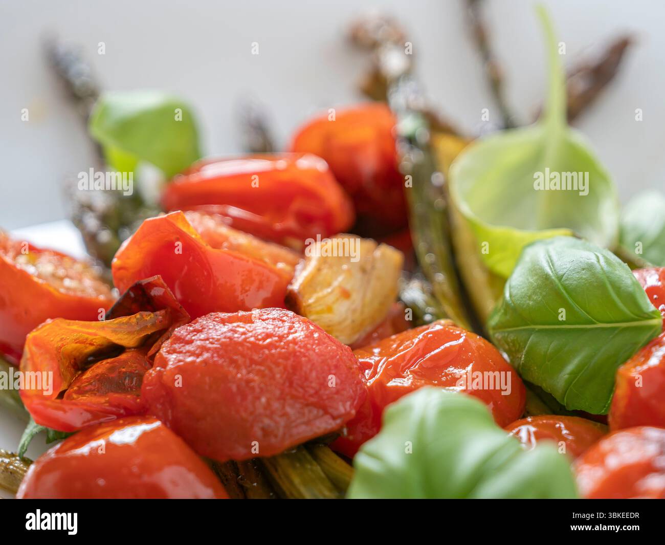 Asperges grillées savoureuses avec tomates mûres et feuilles de basilic frais, une option végétarienne parfaite pour les mangeurs soucieux de leur santé. Banque D'Images